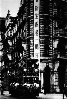 1942年12月25日，大日本帝國香港占領地政府慶祝所謂「新生香港」一週年，底部掛滿日本國旗、頂部插有日本軍旗的電車駛經中環書信館（環球大廈現址）