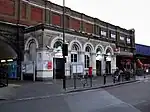 A white building with a rectangular, white sign reading "Vauxhall" in black letters and four bicycles in front all under a grey sky